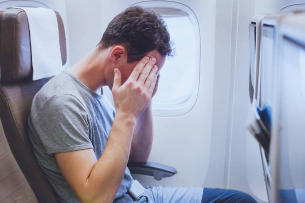 Man with a headache on a plane.